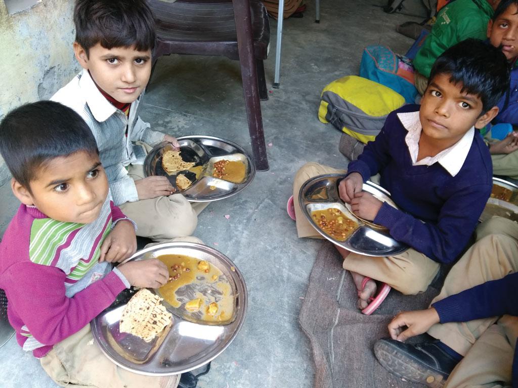 हरियाणा के फरीदाबाद के जिले के अजरौंदा गांव में स्थित प्राइमरी स्कूल में मिड डे मील योजना के तहत मिलने वाला भोजन करते छात्र (अर्चना)