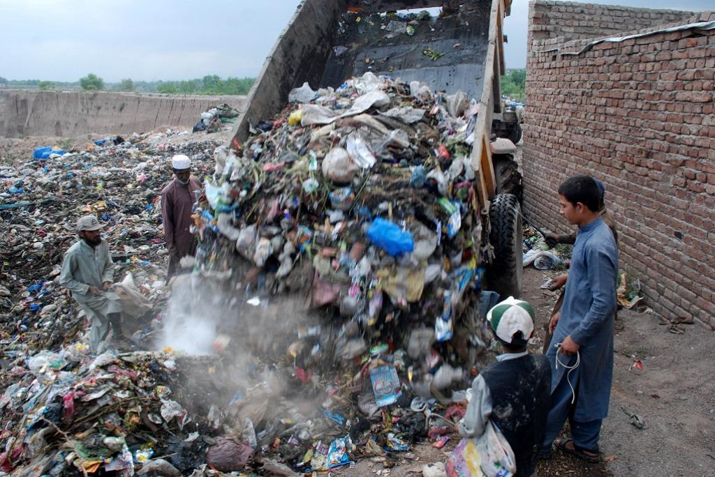 Scavengers gather as a rubbish-laden vehicle is unloaded at new solid waste dumping site in Peshawar, quite far away from populated areas. Credit: Adeel Saeed