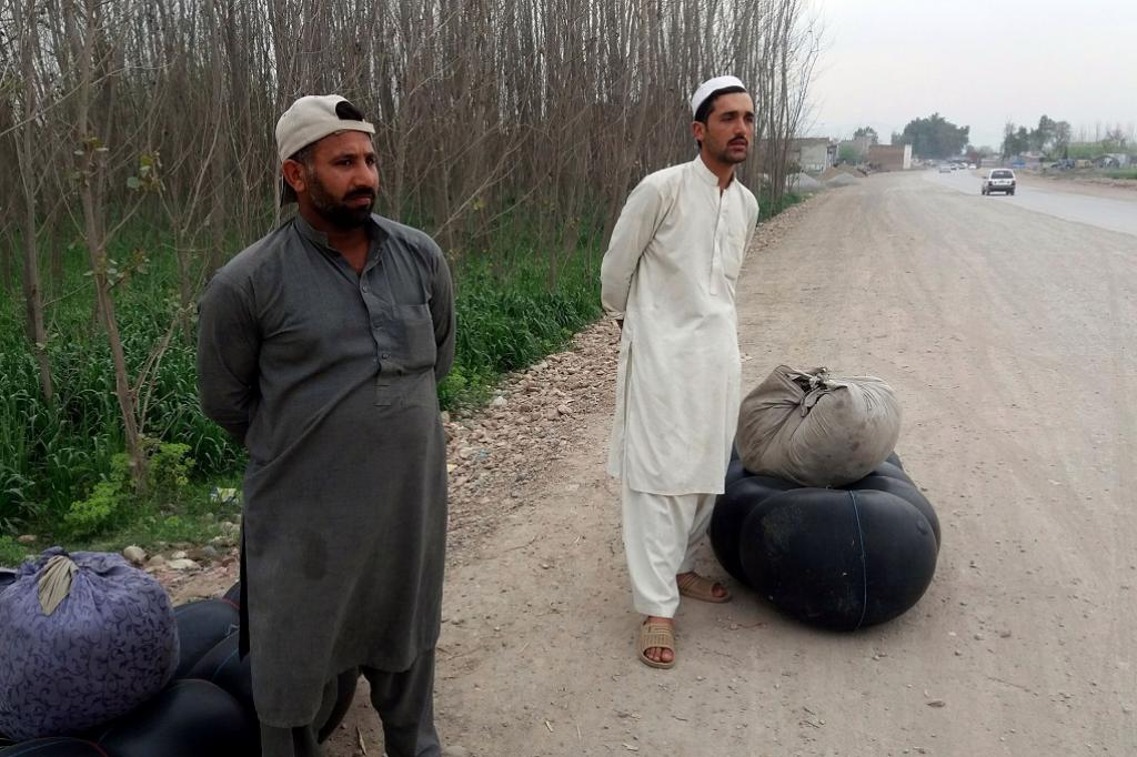 Two fishermen along with their gadgets including inflated plastic tube and net waiting for public transport on the outskirts of Peshawar to travel to Michni and fish for Sher Mahi. Credit: Adeel Saeed