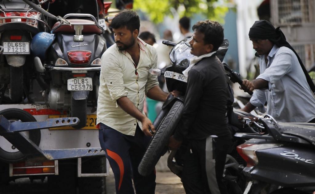Two men lifting a vehicle parked in a No Parking zone in Sarojini Nagar. They are not wearing masks. Photo: Vikas Choudhary / CSE