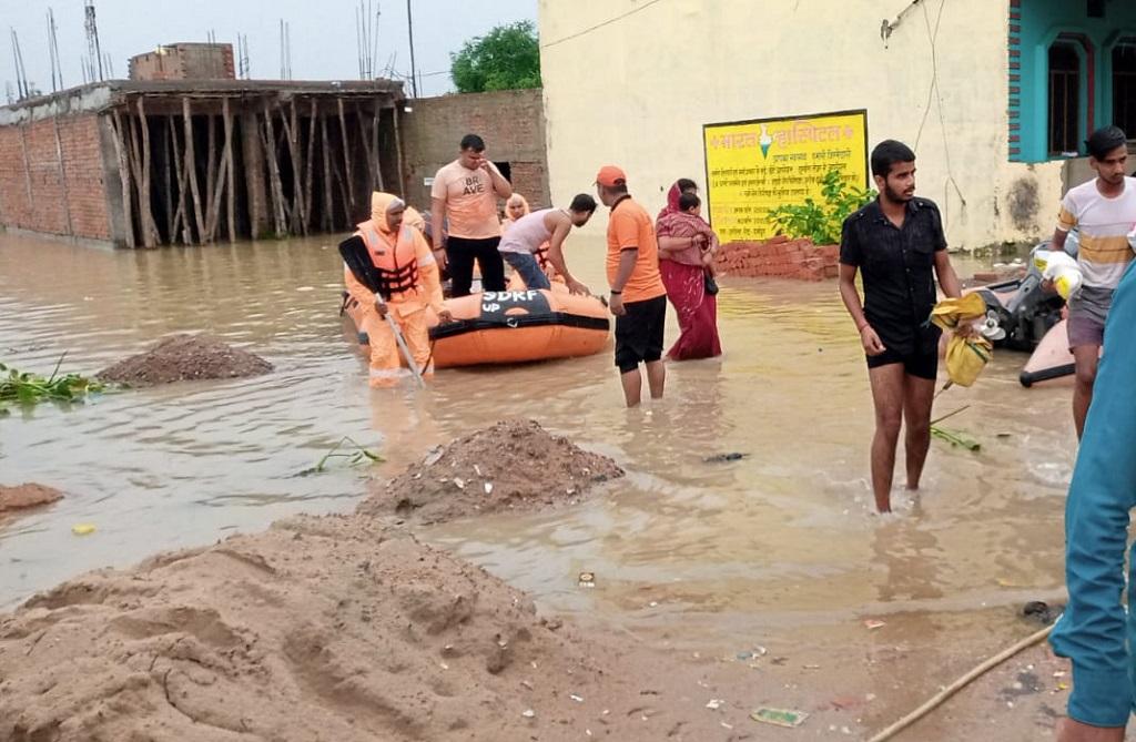 उत्तर प्रदेश के बलरामपुर में बाढ़ में फंसे लगभग लोगों को निकालते एसडीआरएफ के कर्मचारी। फोटो: twitter@sdrf_up उत्तर प्रदेश के बलरामपुर में बाढ़ में फंसे लगभग लोगों को निकालते एसडीआरएफ के कर्मचारी। फोटो: twitter@sdrf_up